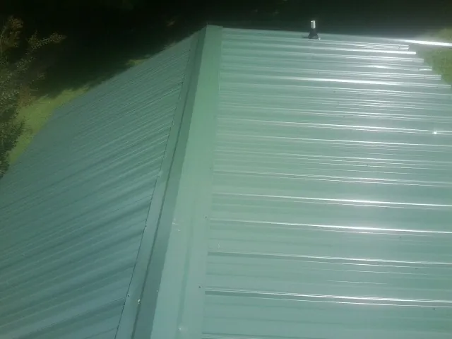 New green metal panels meeting at the ridge of a roof — Flat Roof Repair work by our crew in Rocky Ford