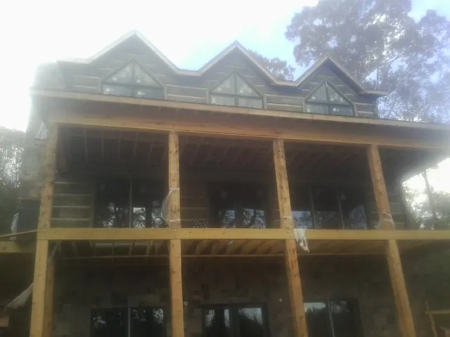 Dormers and porch framing on a large log home under construction — Roof Coating work by our crew in Rocky Ford