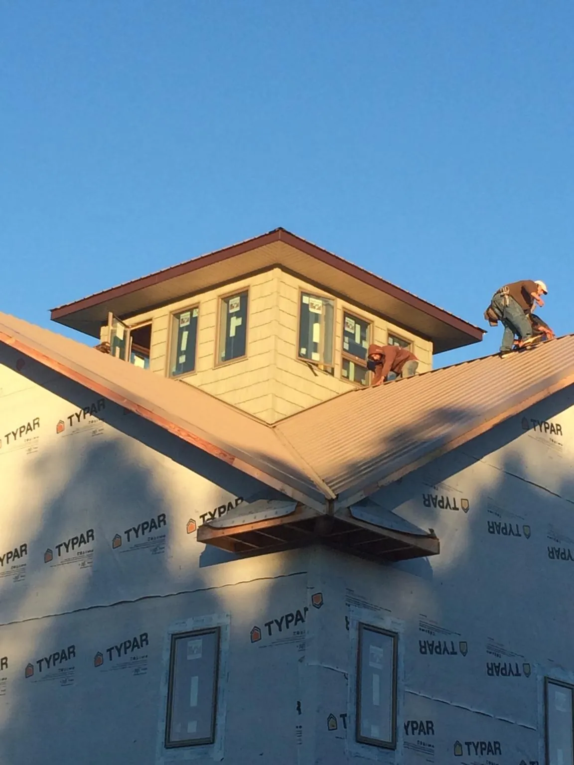 Roofers working around a rooftop cupola on a new metal roof at sunset — Roof Waterproofing in Rocky Ford by Roofing Brothers